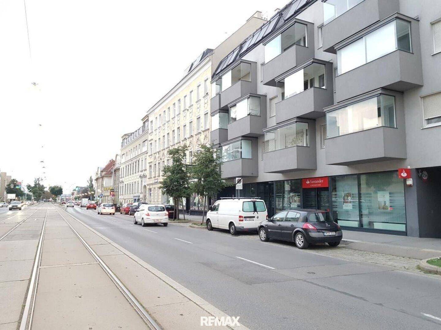 Straßenansicht eines modernen Gebäudes mit Geschäften im Erdgeschoss und Wohnungen darüber.