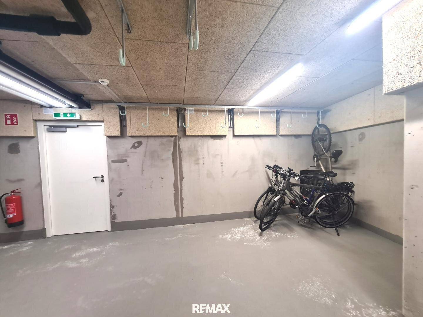 Geräumiger Fahrradraum im Untergeschoss mit Abstellmöglichkeiten für mehrere Fahrräder und Haken an der Wand.