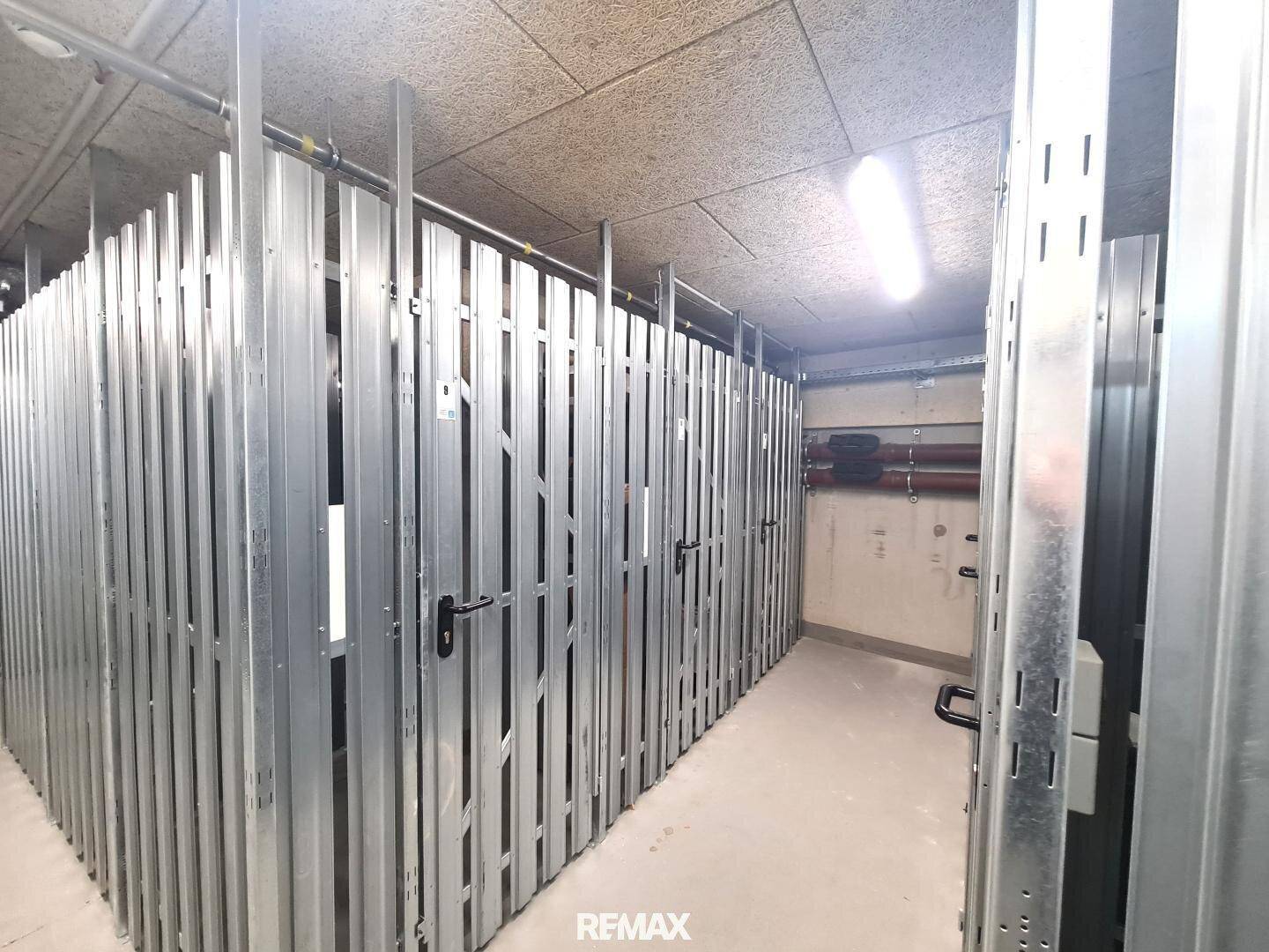 Reihen von individuellen Lagerabteilen aus Metall in einem gemeinsamen Abstellraum im Untergeschoss.
