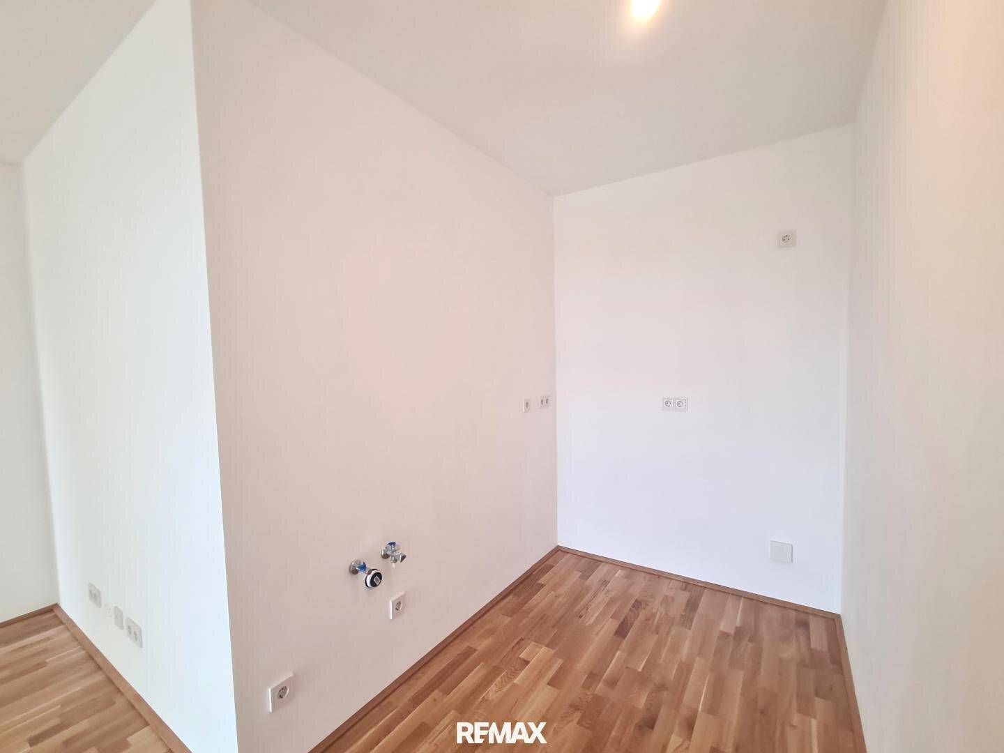 Kleiner, leerer Raum mit Holzboden und Anschlüssen für eine Küche oder einen Hauswirtschaftsraum.