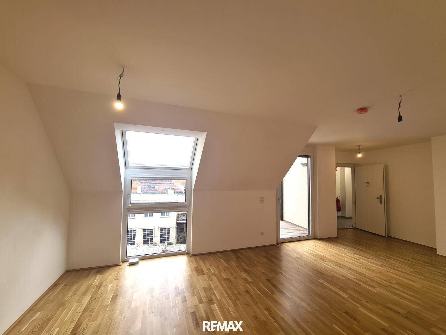 Heller Raum mit Holzboden, Dachfenster und Zugang zu einem Außenbereich, ideal als Schlafzimmer.