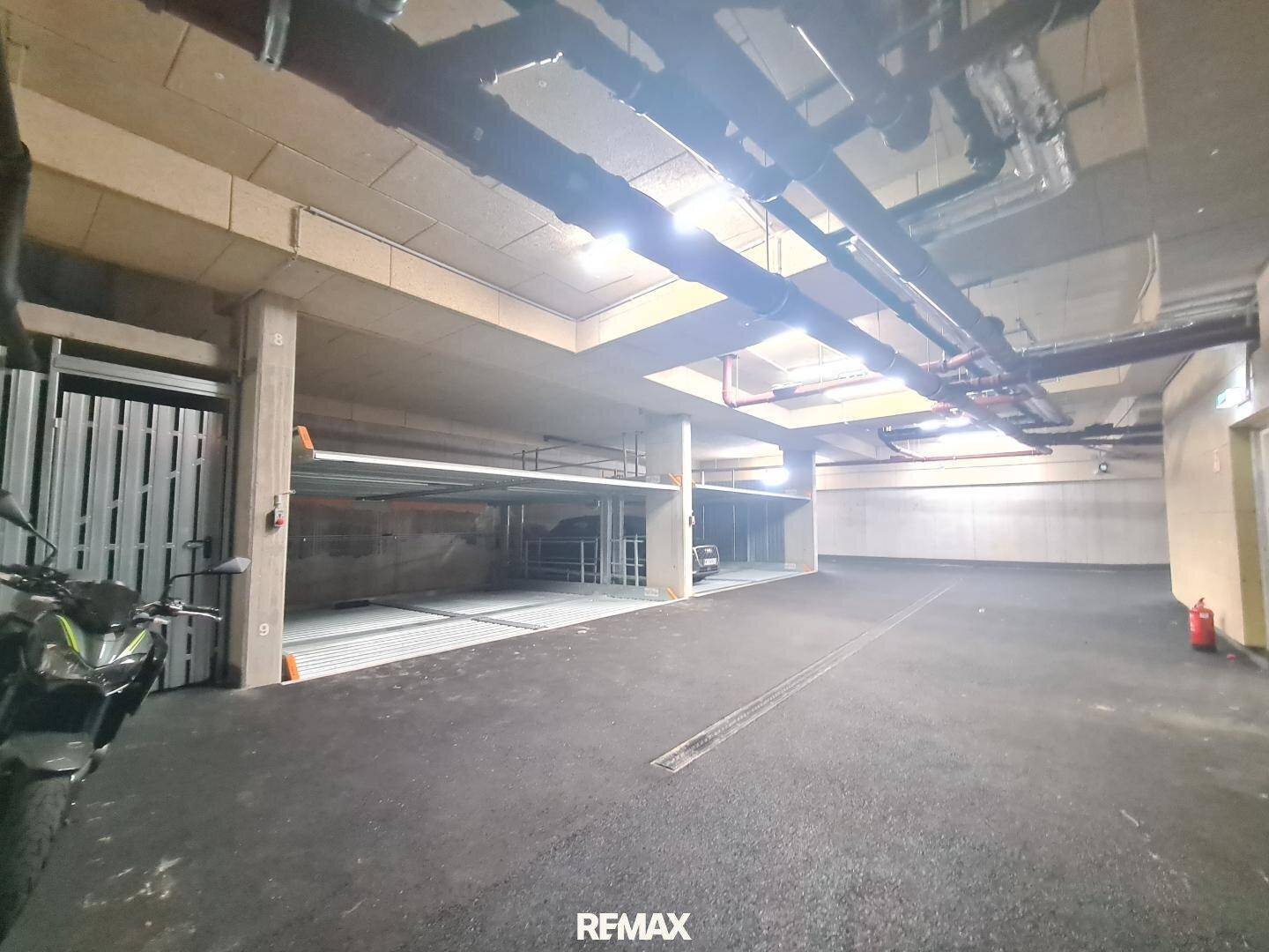Tiefgarage mit mehreren Parkplätzen und Motorrad, gut beleuchtet und geräumig.