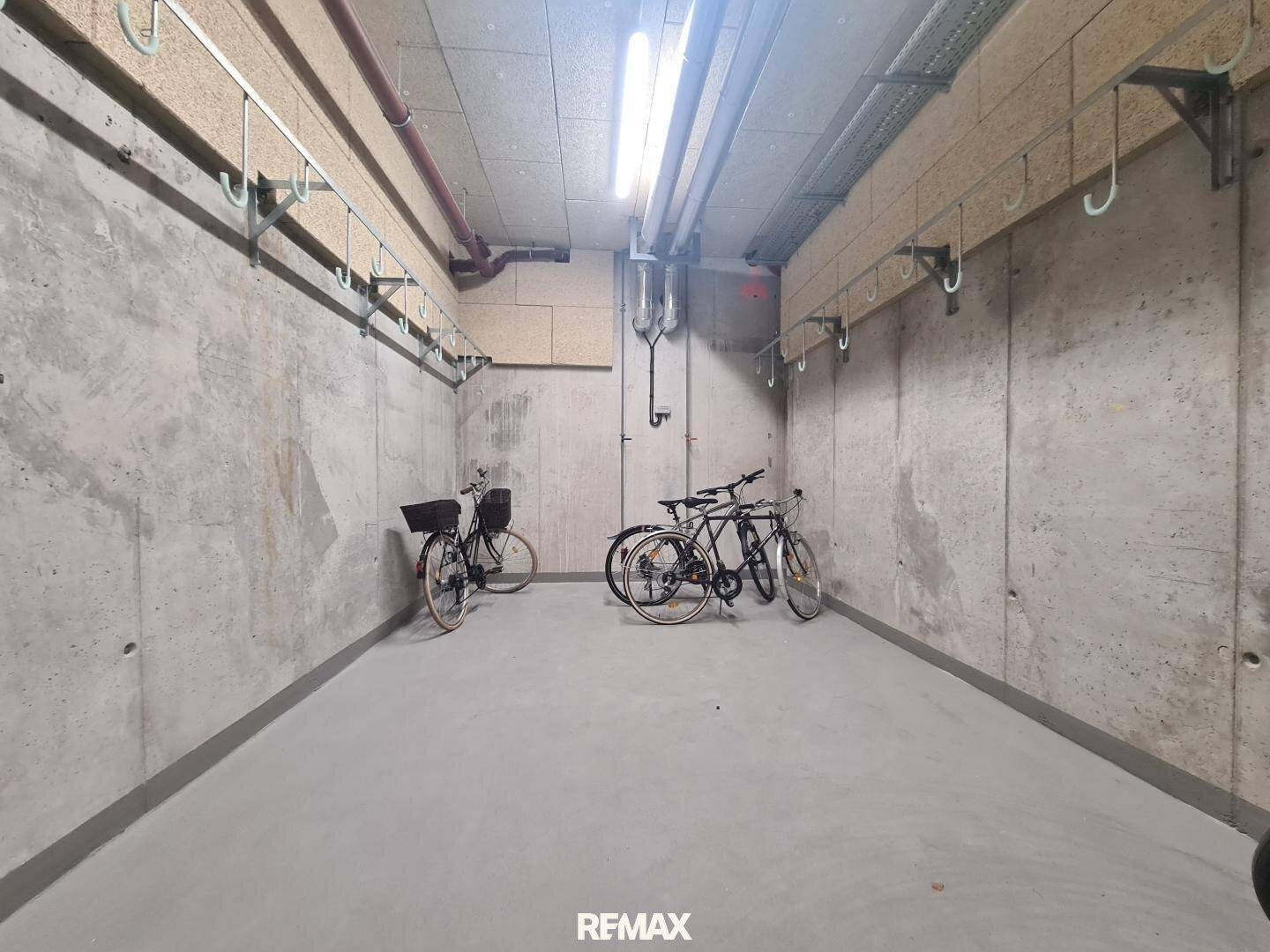 Gemeinschaftlicher Fahrradraum im Keller mit Betonwänden und mehreren Fahrrädern.