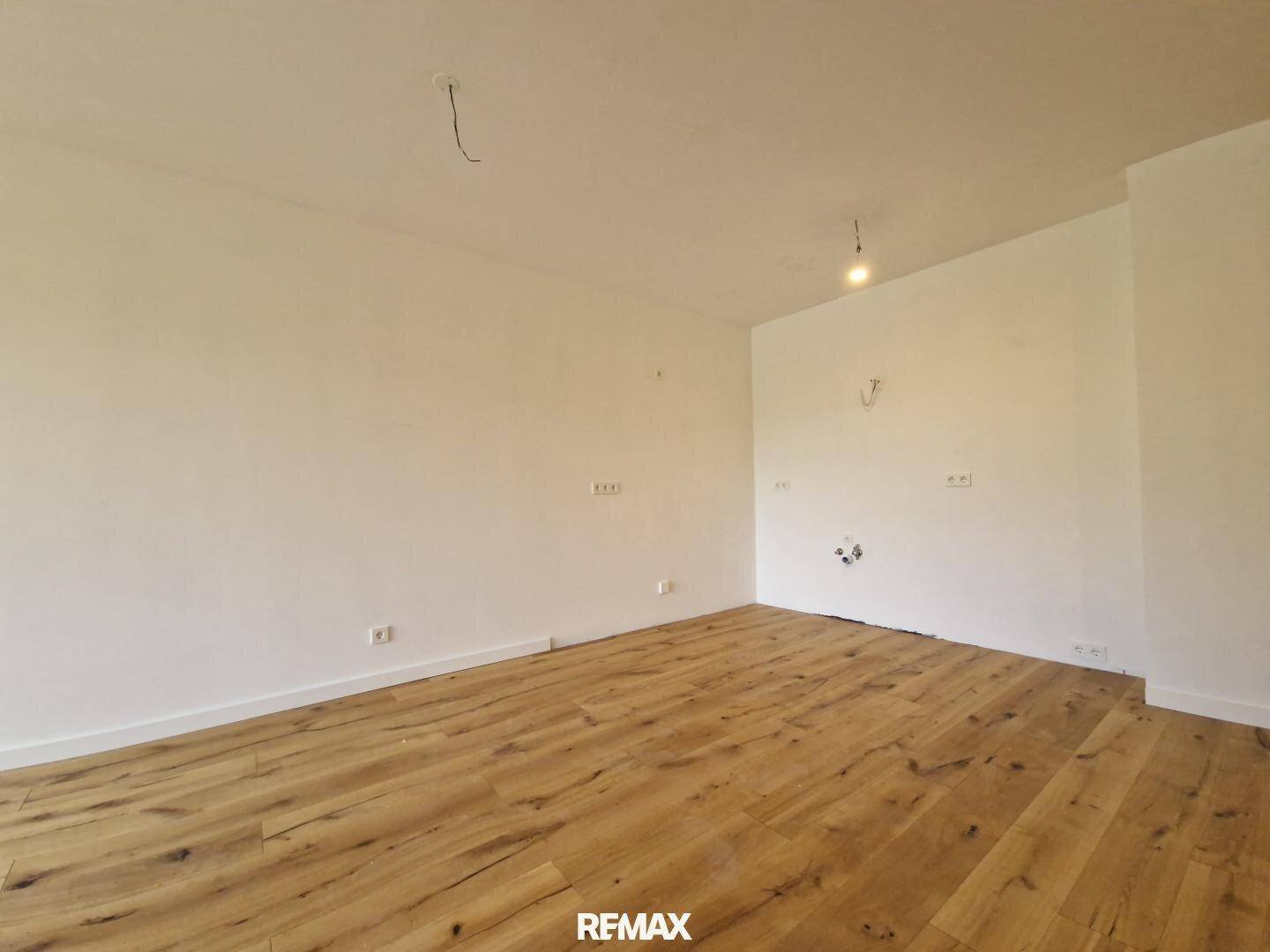 Leerer Raum mit Holzboden und weißen Wänden, bereit für individuelle Gestaltung.