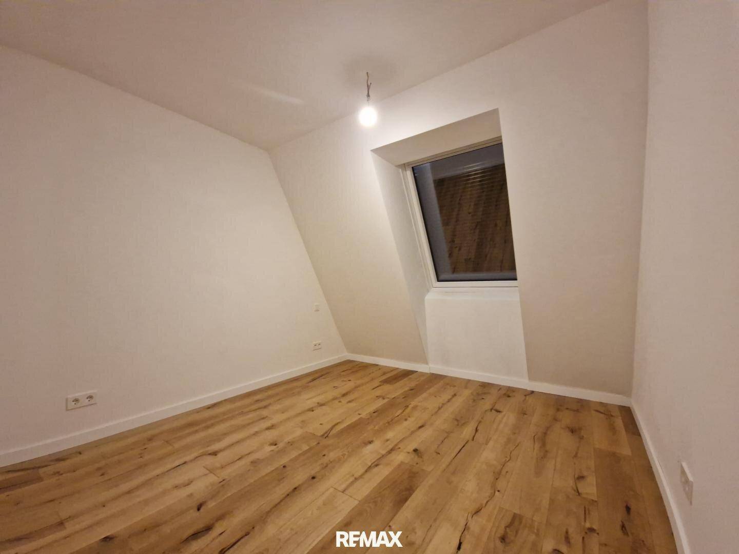 Gemütliches Schlafzimmer mit Holzboden und Dachschräge, ideal für ein ruhiges Ambiente.