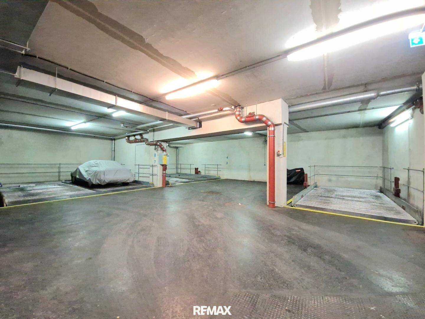 Geräumige Tiefgarage mit mehreren Doppelparkern und sichtbaren Installationen an der Decke.