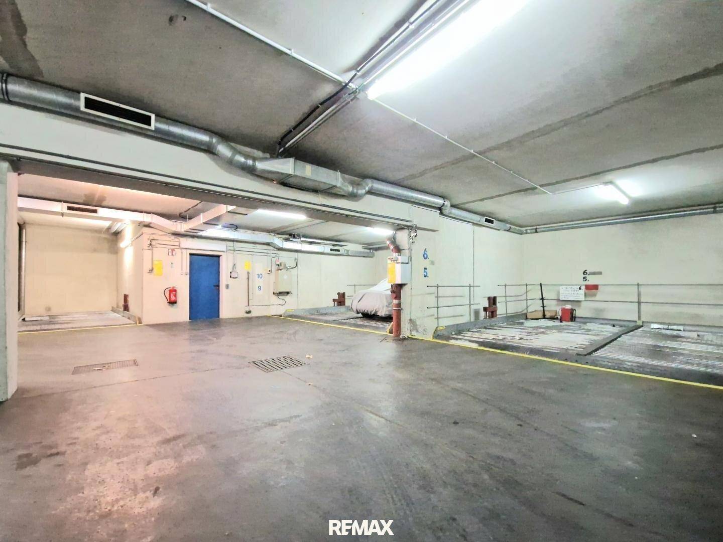 Geräumige Tiefgarage mit mehreren Doppelparkern und einem blauen Zugangstor.