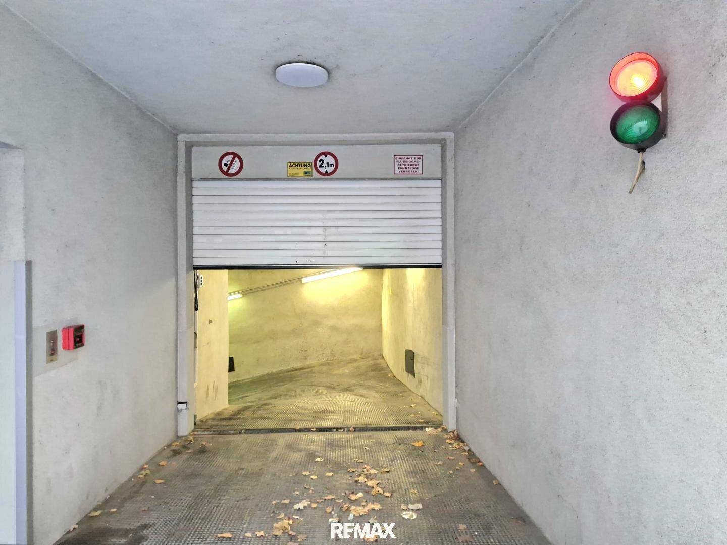 Einfahrt zur Tiefgarage mit Rolltor, Ampel und Höhenbegrenzungsschild.
