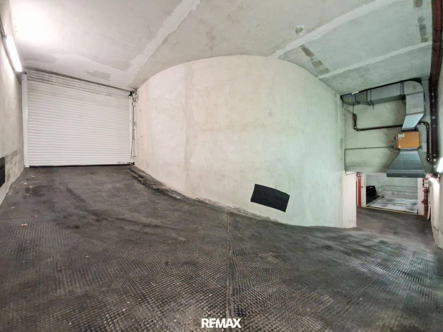 Zufahrtsrampe in der Tiefgarage mit Rolltor und Betonwänden.