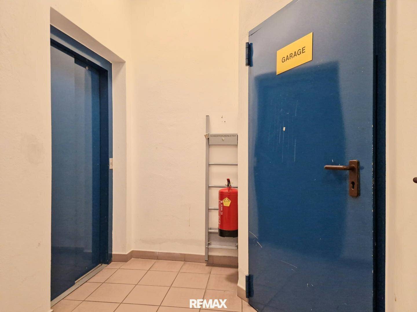 Flur mit Zugangstür zur Garage und einem Feuerlöscher an der Wand.