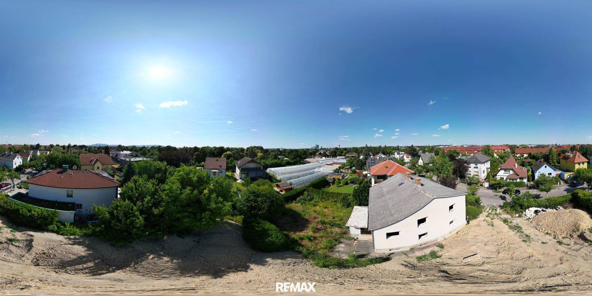 Panorama-Luftaufnahme der Wohngegend mit Häusern, Grünflächen und weitem Himmel.