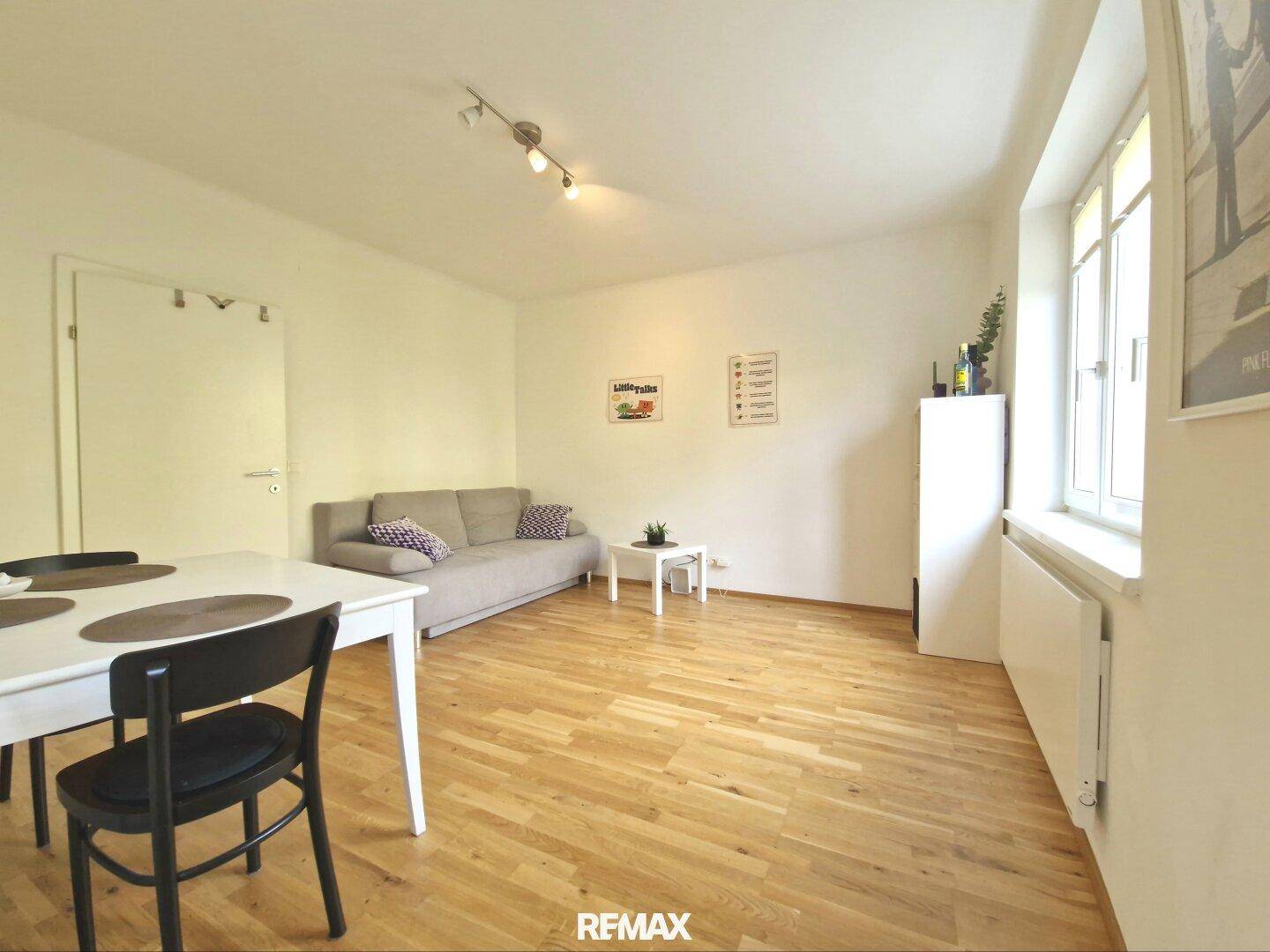 Gemütlicher Wohn-Essbereich mit Sofa, Esstisch und hellem Holzparkett.