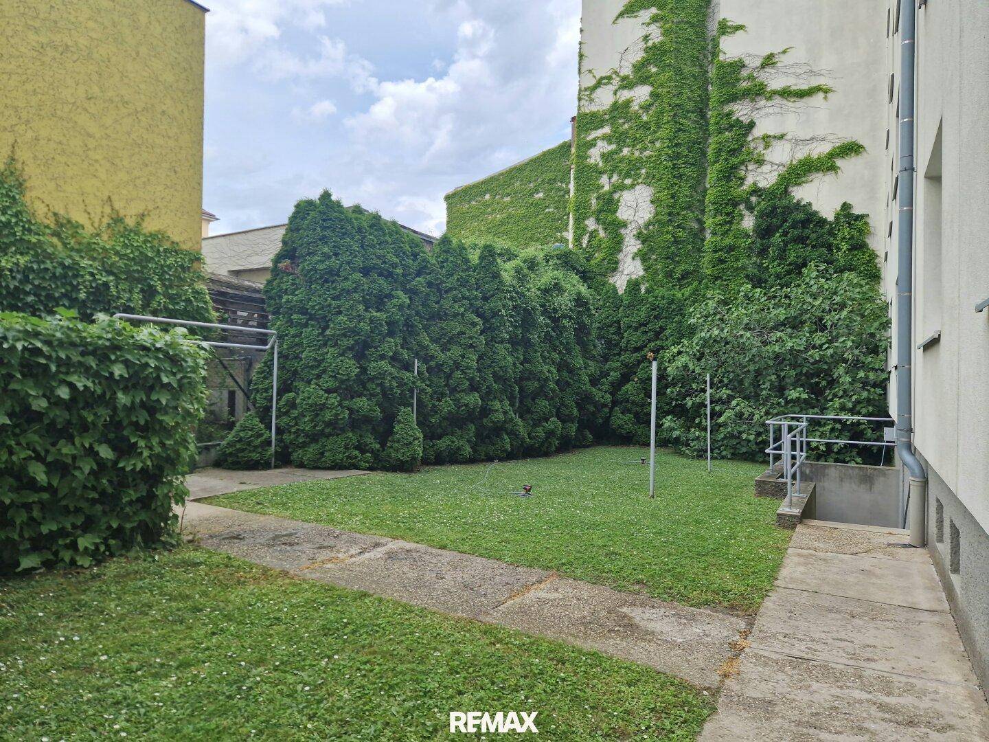 Gepflegter Gartenbereich mit Rasenfläche und hohen Hecken für Privatsphäre.