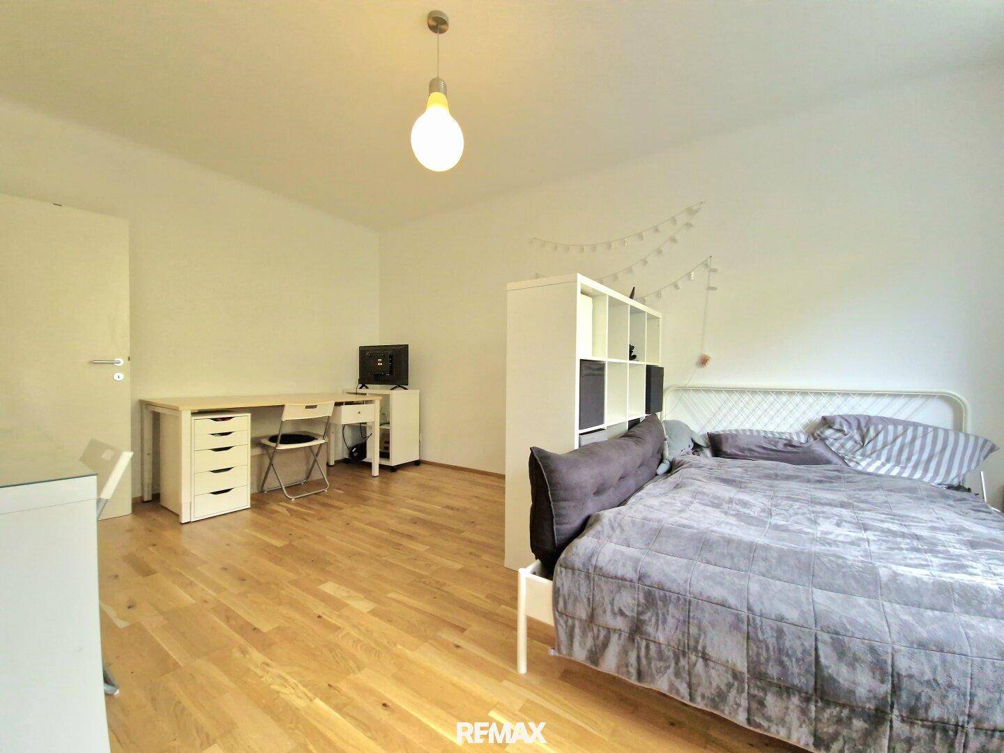 Geräumiges Schlafzimmer mit Holzfußboden, Schreibtisch und viel Platz für persönliche Gestaltung.