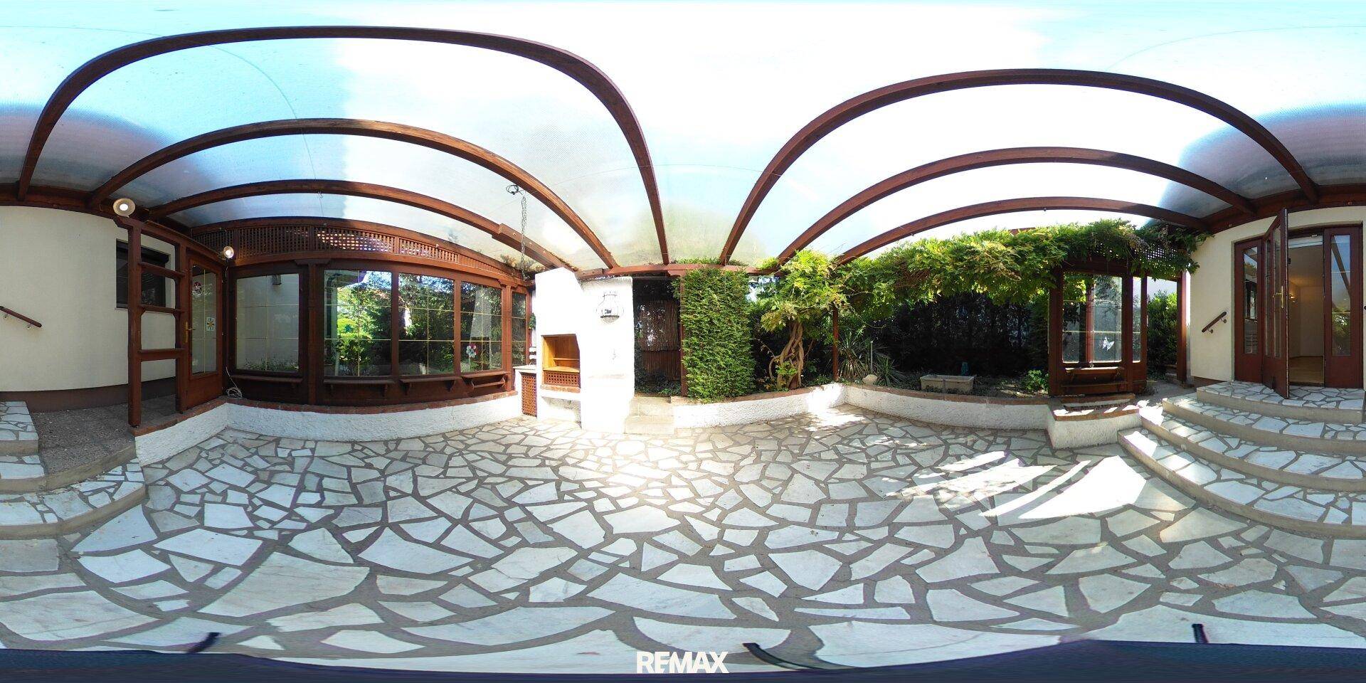 Panoramaansicht der überdachten Terrasse mit Mosaikboden und integriertem Grillbereich.