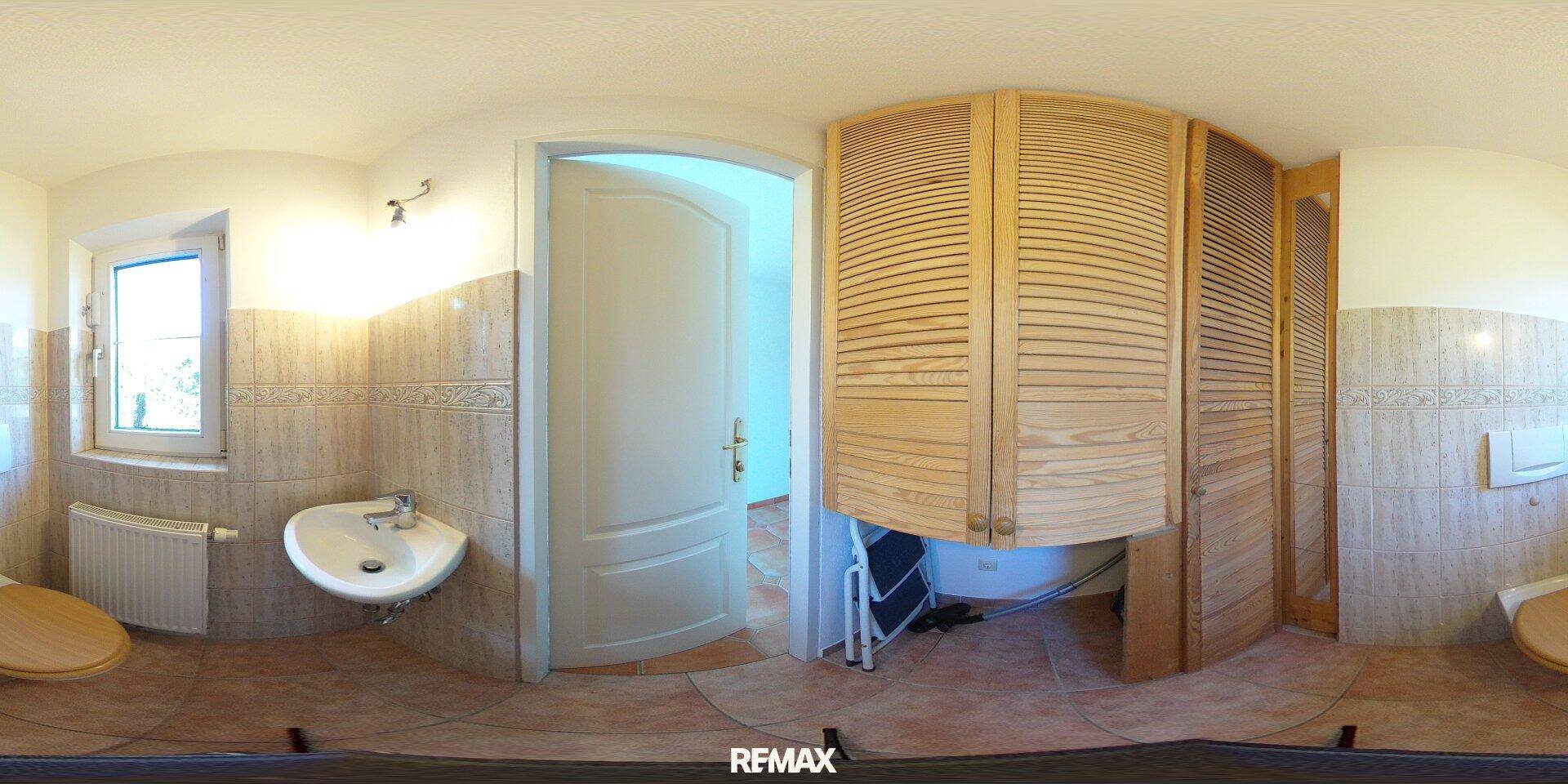 Kleines Gäste-WC mit Fenster, Waschbecken und praktischen Holzschränken.