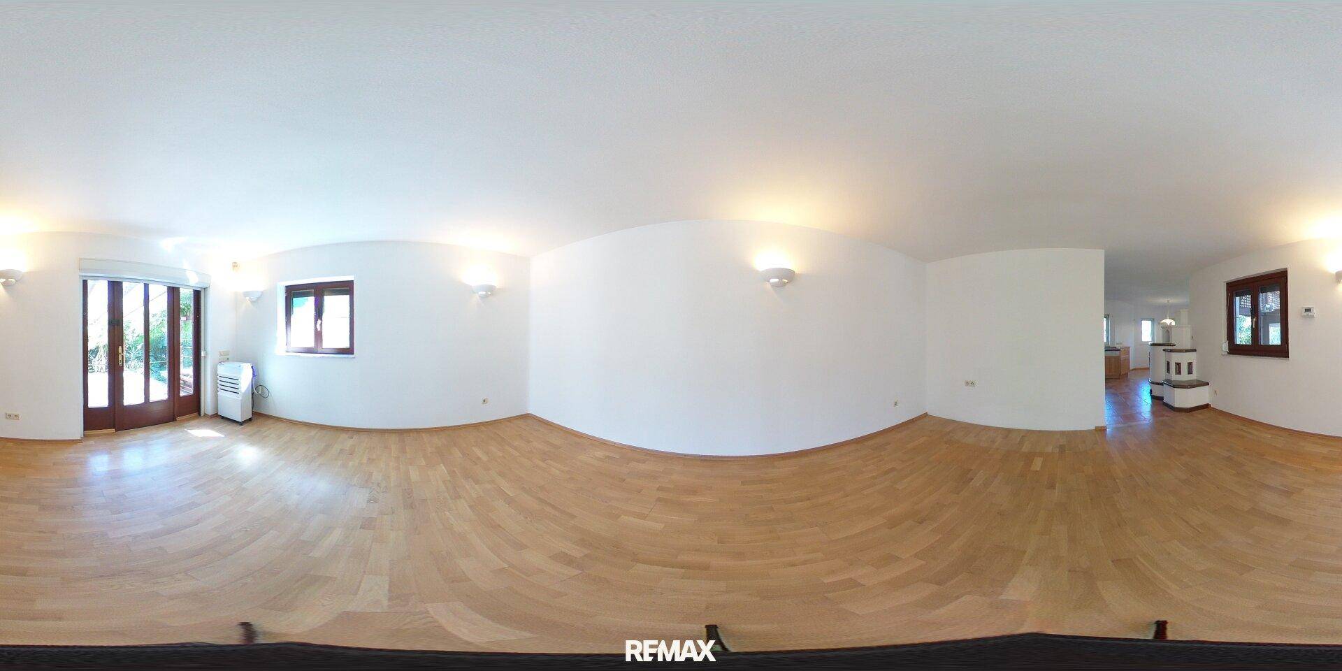 Helles Wohnzimmer mit Parkettboden, weißen Wänden und Zugang zum Außenbereich.