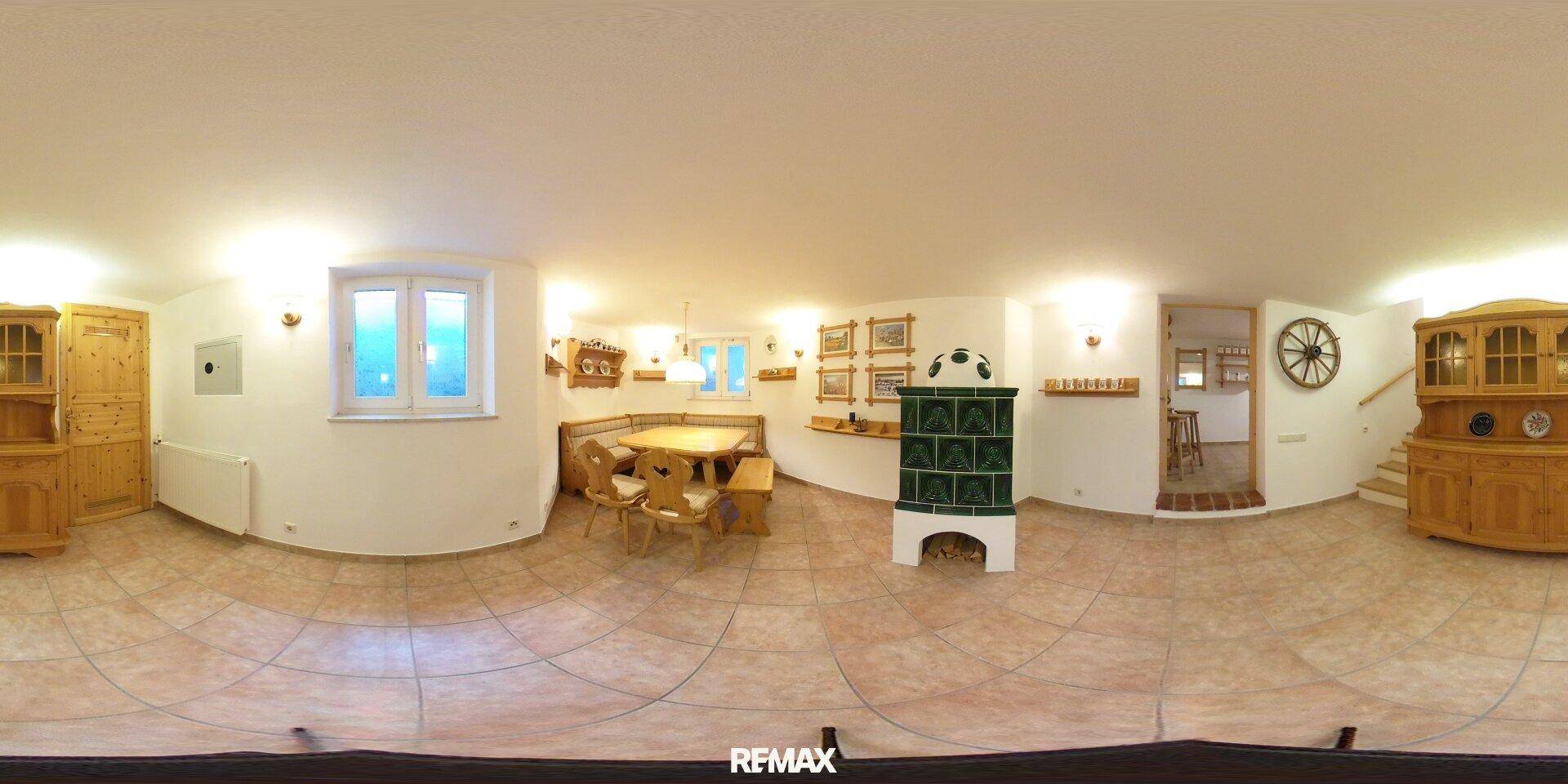 Gemütlicher Kellerraum mit Essbereich, grünem Kachelofen und rustikalen Holzmöbeln.