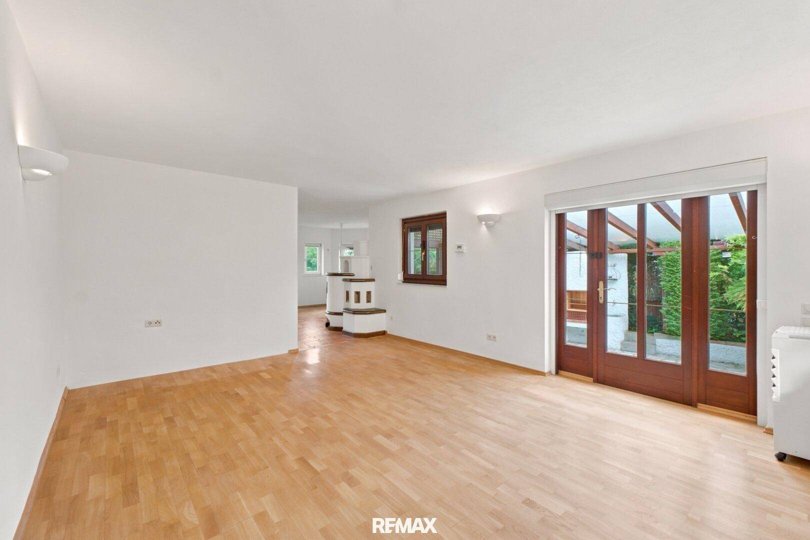 Helles Wohnzimmer mit Parkettboden und Zugang zur überdachten Terrasse.