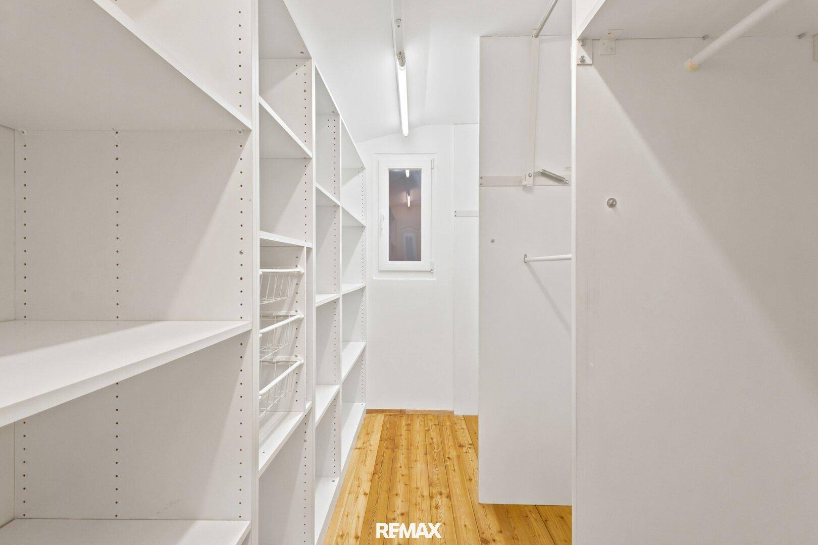 Praktischer begehbarer Kleiderschrank mit vielen Regalen und einem kleinen Fenster für Belüftung.