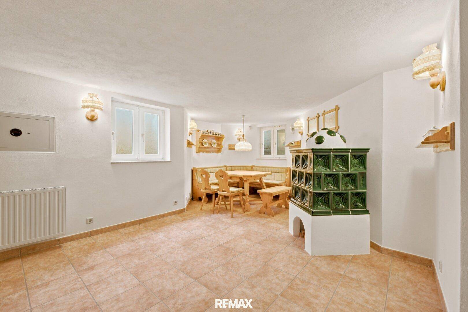 Gemütlicher Essbereich im Keller mit traditionellem Kachelofen und rustikalen Holzmöbeln.