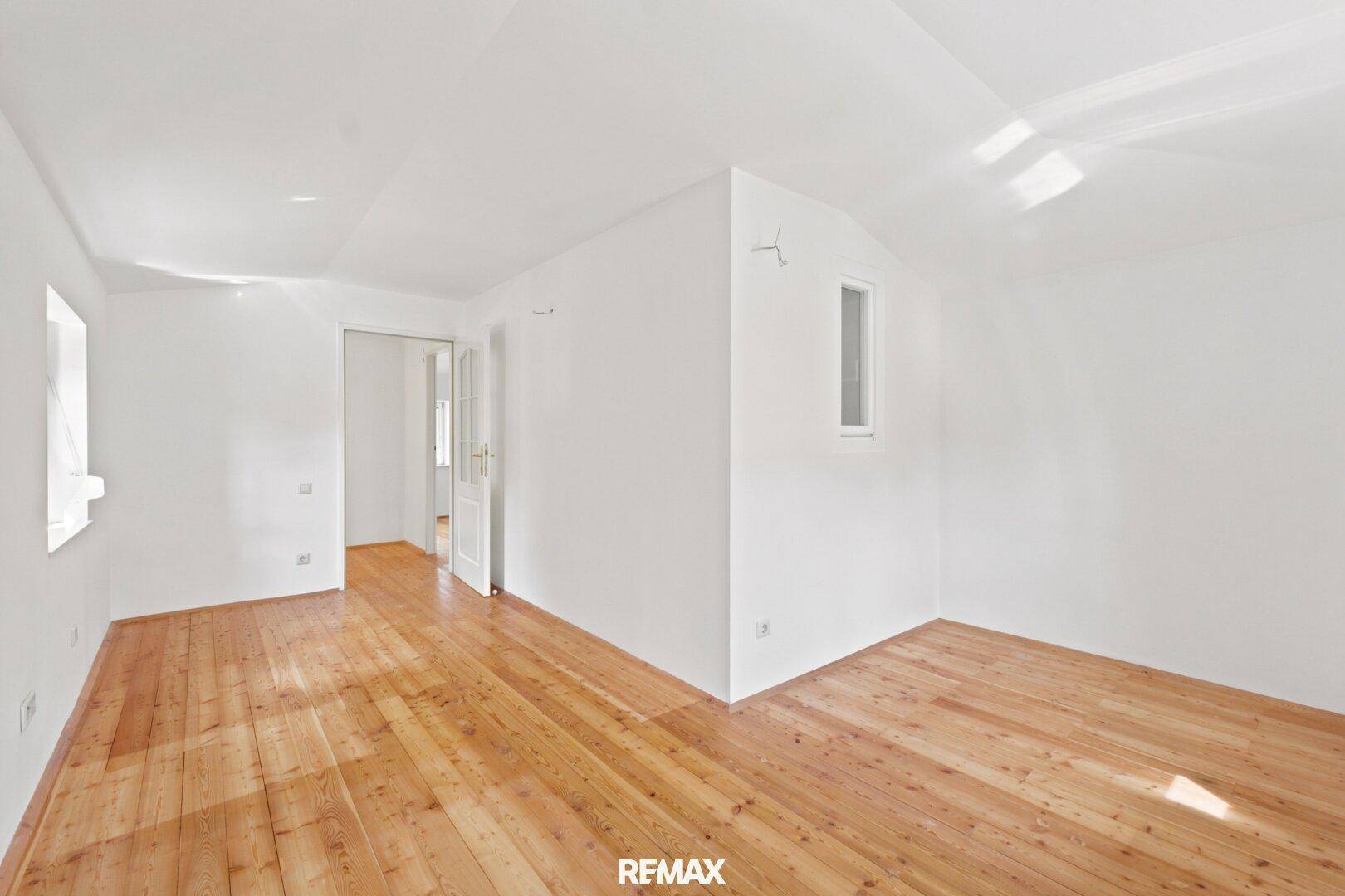 Geräumiges Schlafzimmer mit Holzdielenboden und weiß gestrichenen Wänden, bereit zur individuellen Gestaltung.