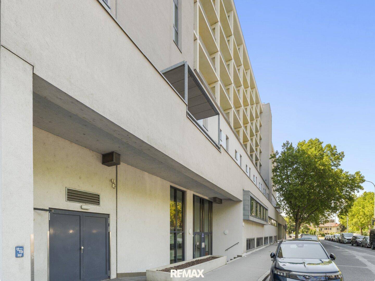 Moderne Gebäudefassade mit klaren Linien und großen Fenstern, direkt an der Straße gelegen.