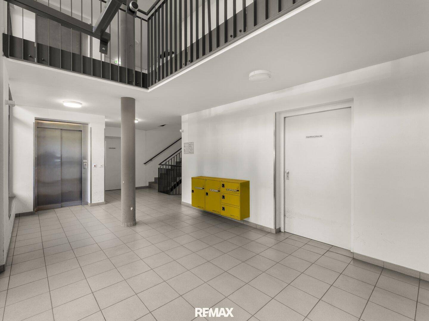 Heller Eingangsbereich mit Fliesenboden, Aufzug und Treppenhaus, modern und funktional.