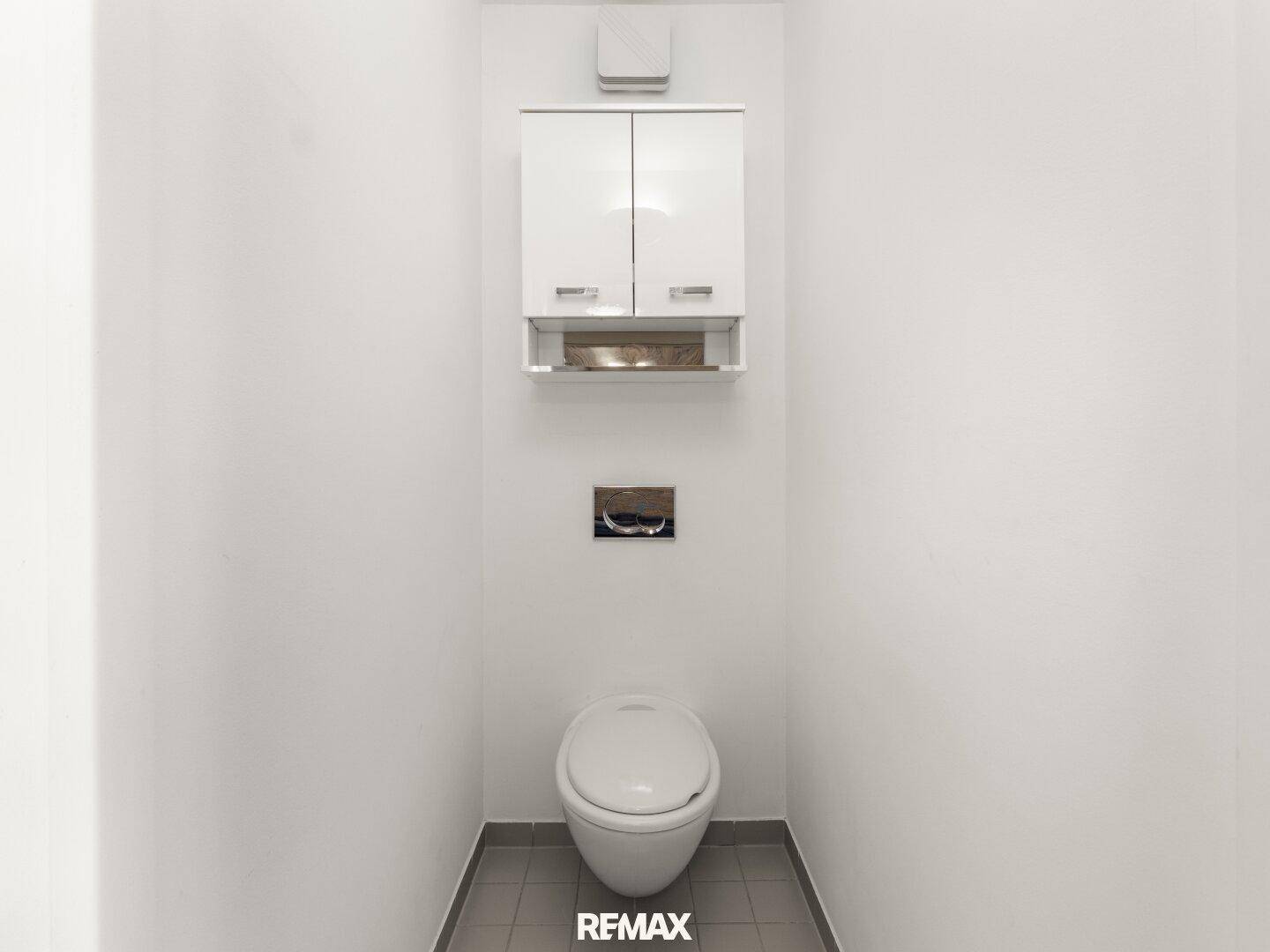 Kleines Gäste-WC mit wandhängender Toilette und praktischem Wandschrank, minimalistisch gestaltet.