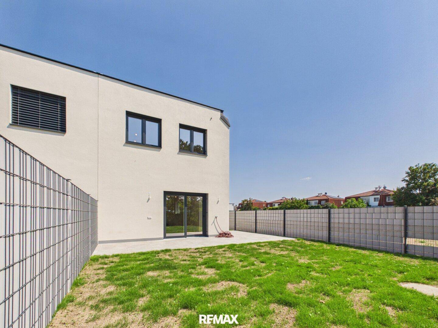 Gartenbereich hinter dem modernen Haus mit Rasenfläche und Blick auf die Fassade.