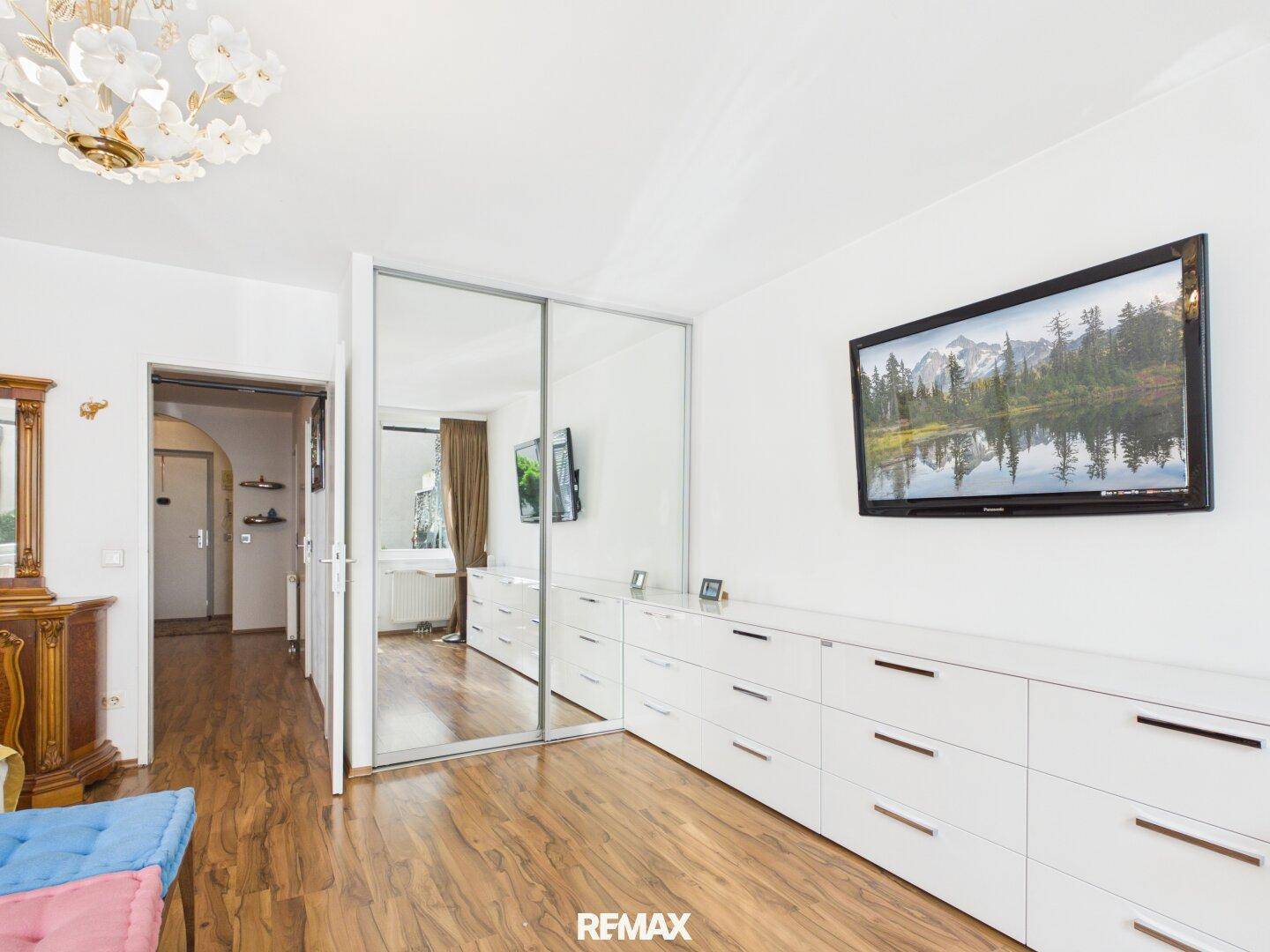 Schlafzimmer mit weißen Kommoden und Spiegelschränken, die den Raum optisch vergrößern und aufhellen.