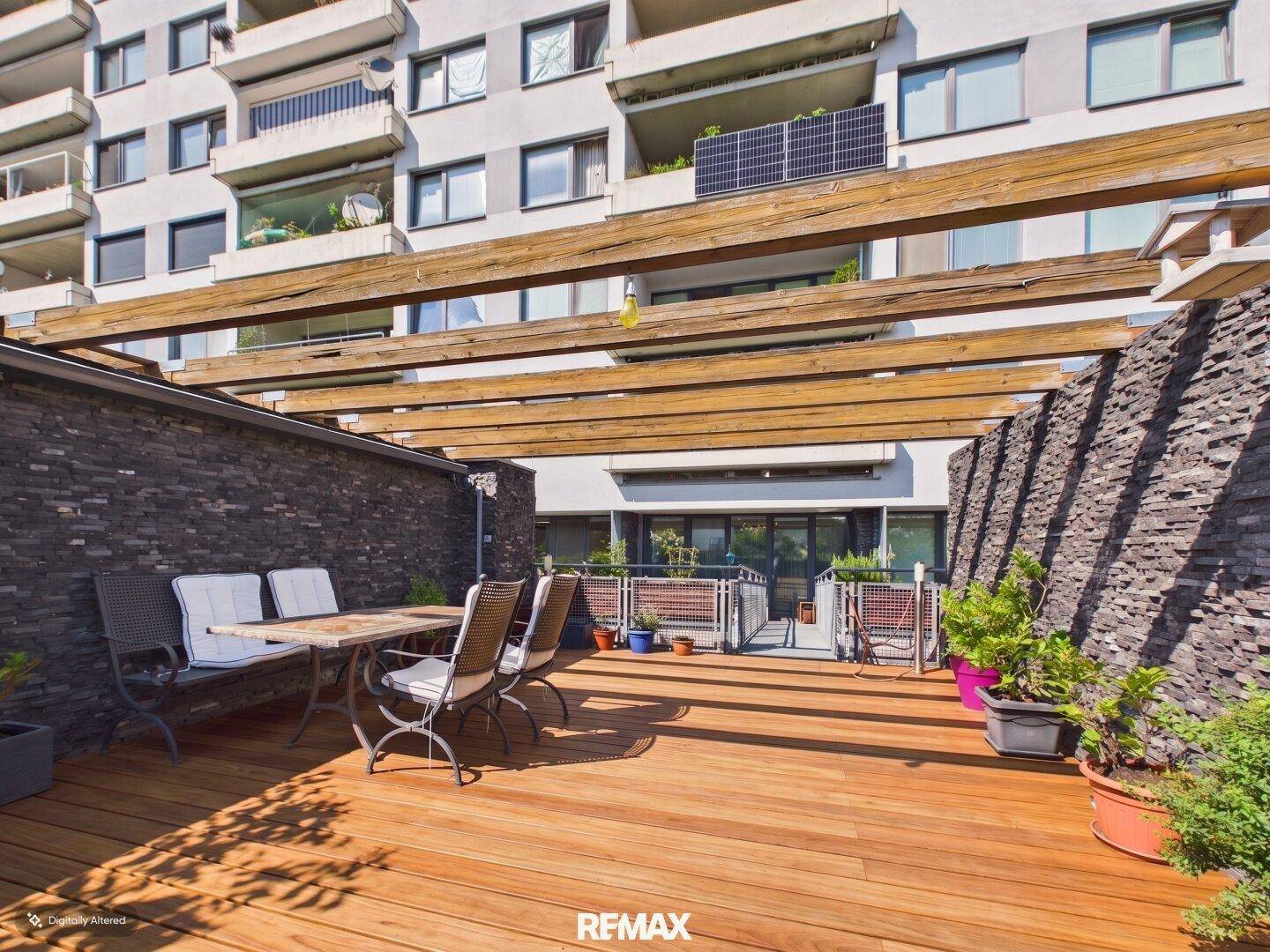 Große Sonnenterrasse mit Holzdeck, Steinmauern und Gartenmöbeln, perfekt für Entspannung.