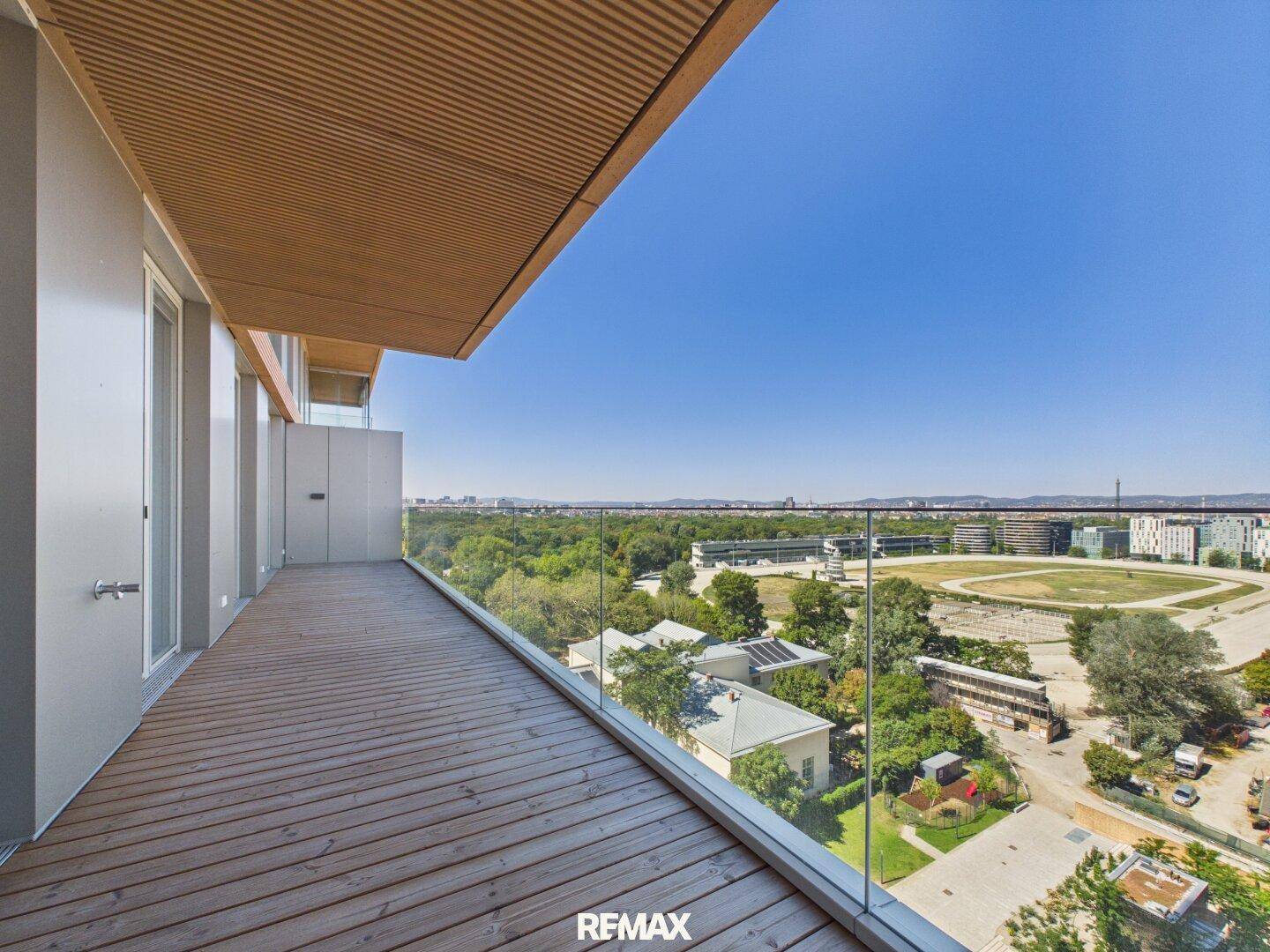 Langer Balkon mit Holzfußboden und Glasbrüstung bietet weite Aussicht.