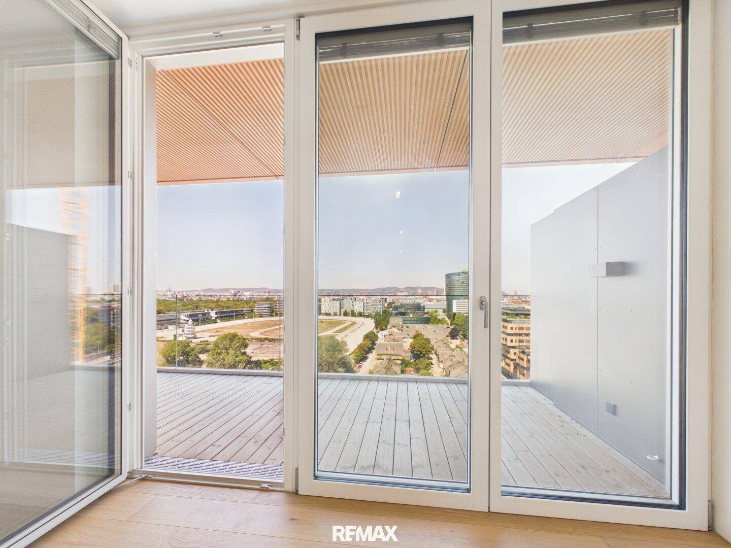 Große Fensterfront mit Blick auf die Stadt und Zugang zu einem Außenbereich.