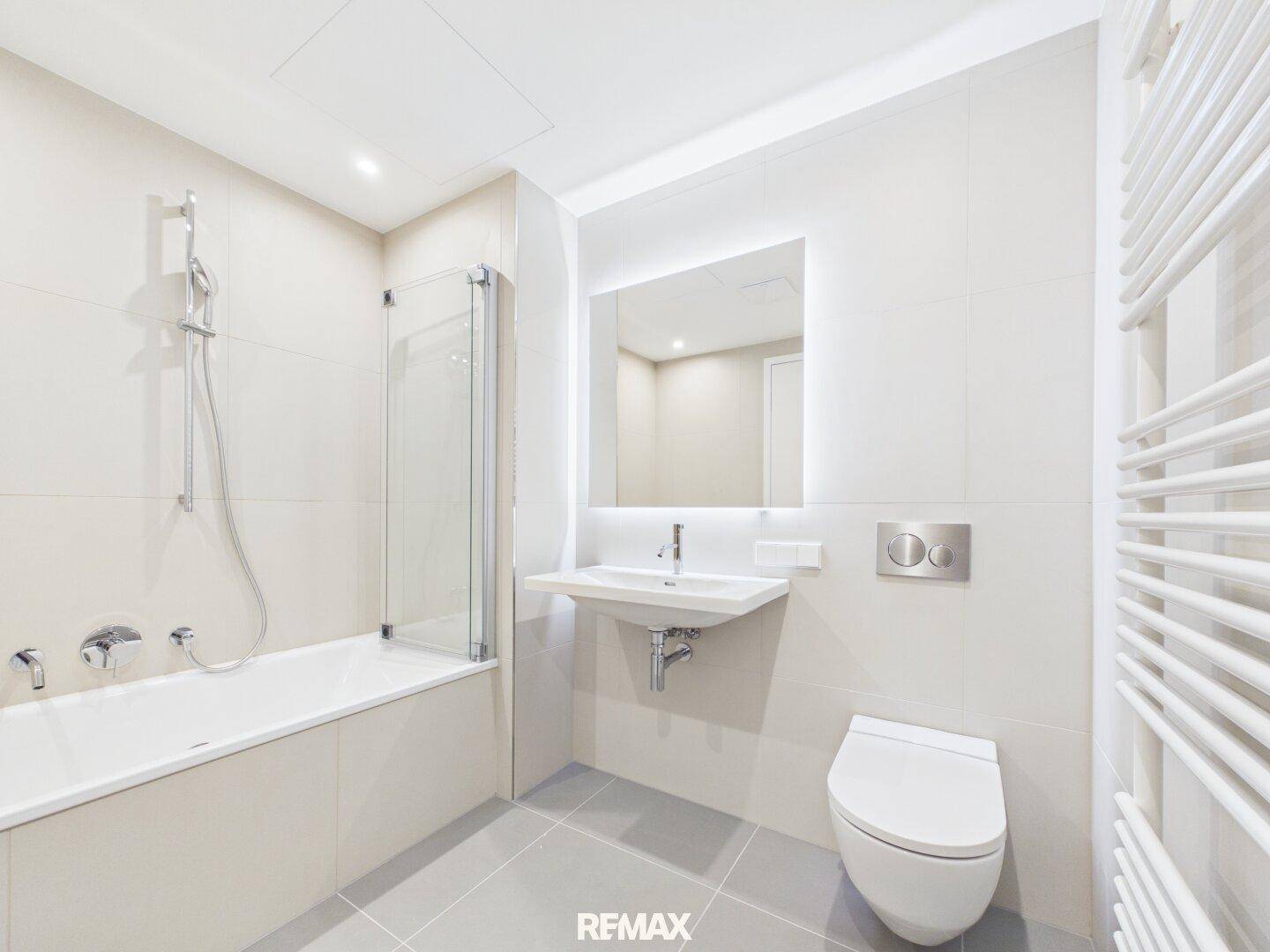 Modernes Badezimmer mit Badewanne, Dusche, WC und beheiztem Handtuchhalter.