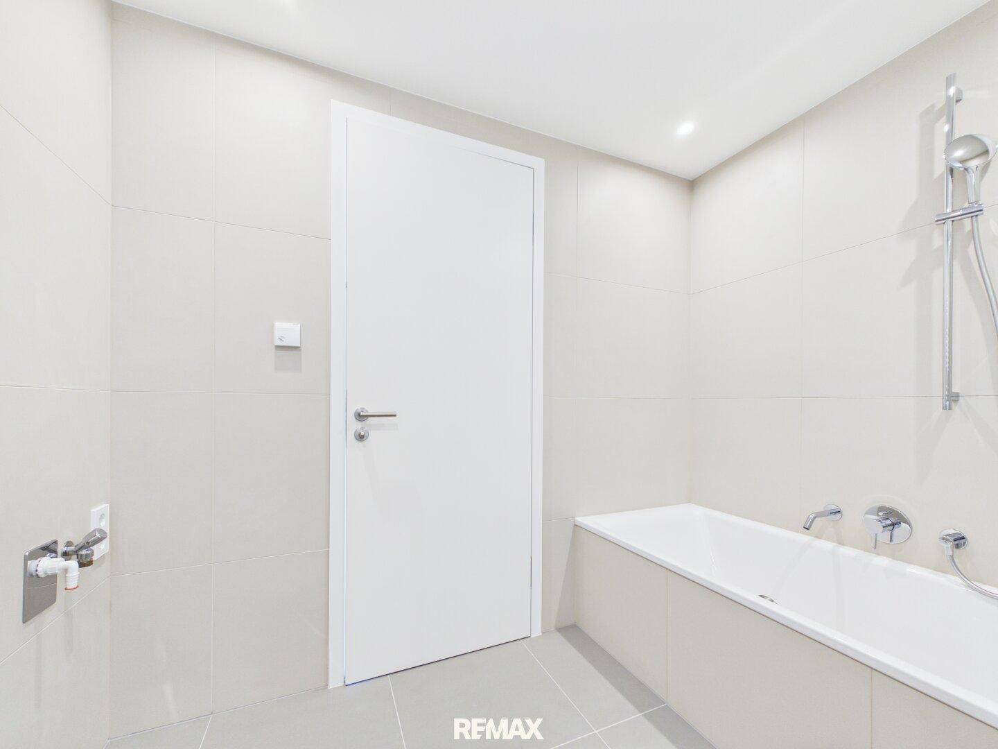 Helles Badezimmer mit Badewanne und modernen Fliesen in neutralen Farben.