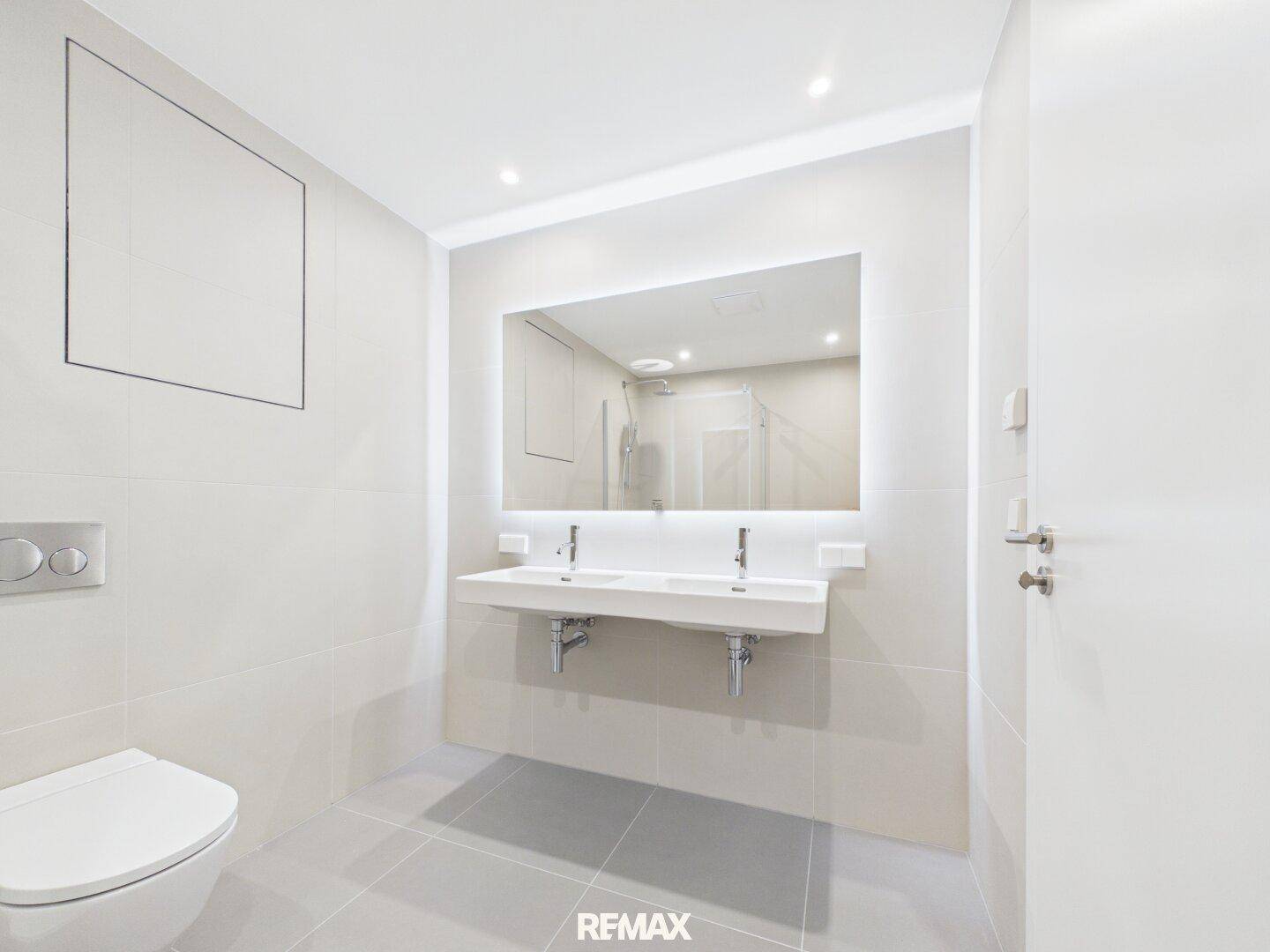 Modernes Badezimmer mit Doppelwaschbecken, großem Spiegel und WC.