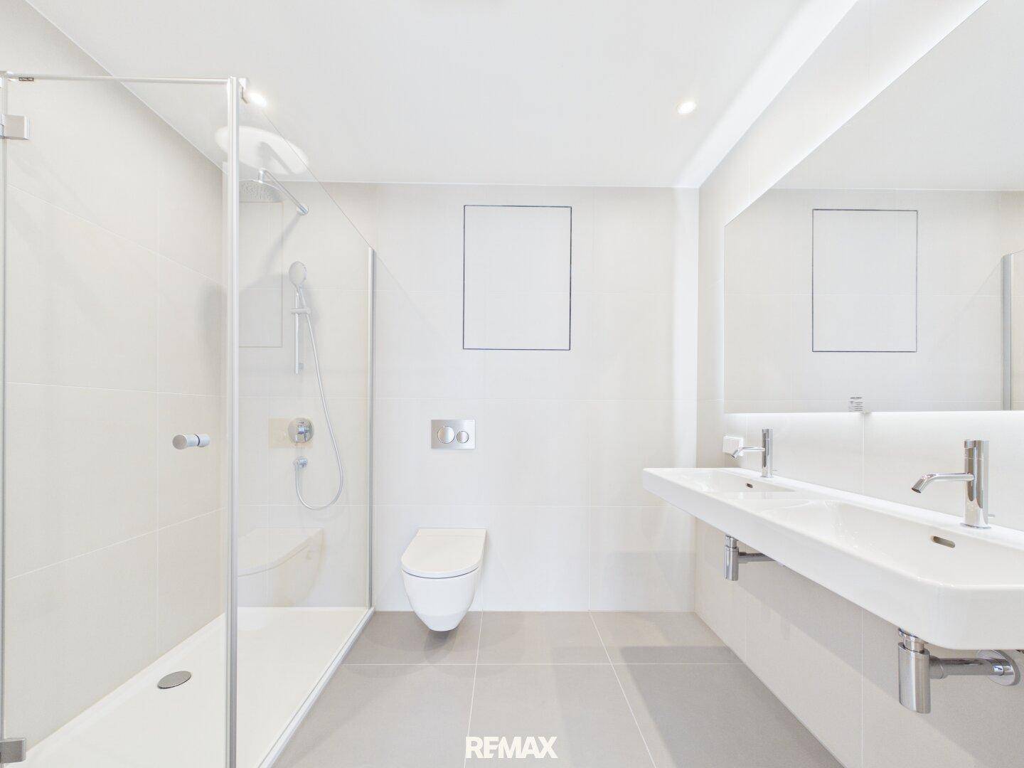 Modernes Badezimmer mit Doppelwaschbecken, ebenerdiger Dusche und WC.