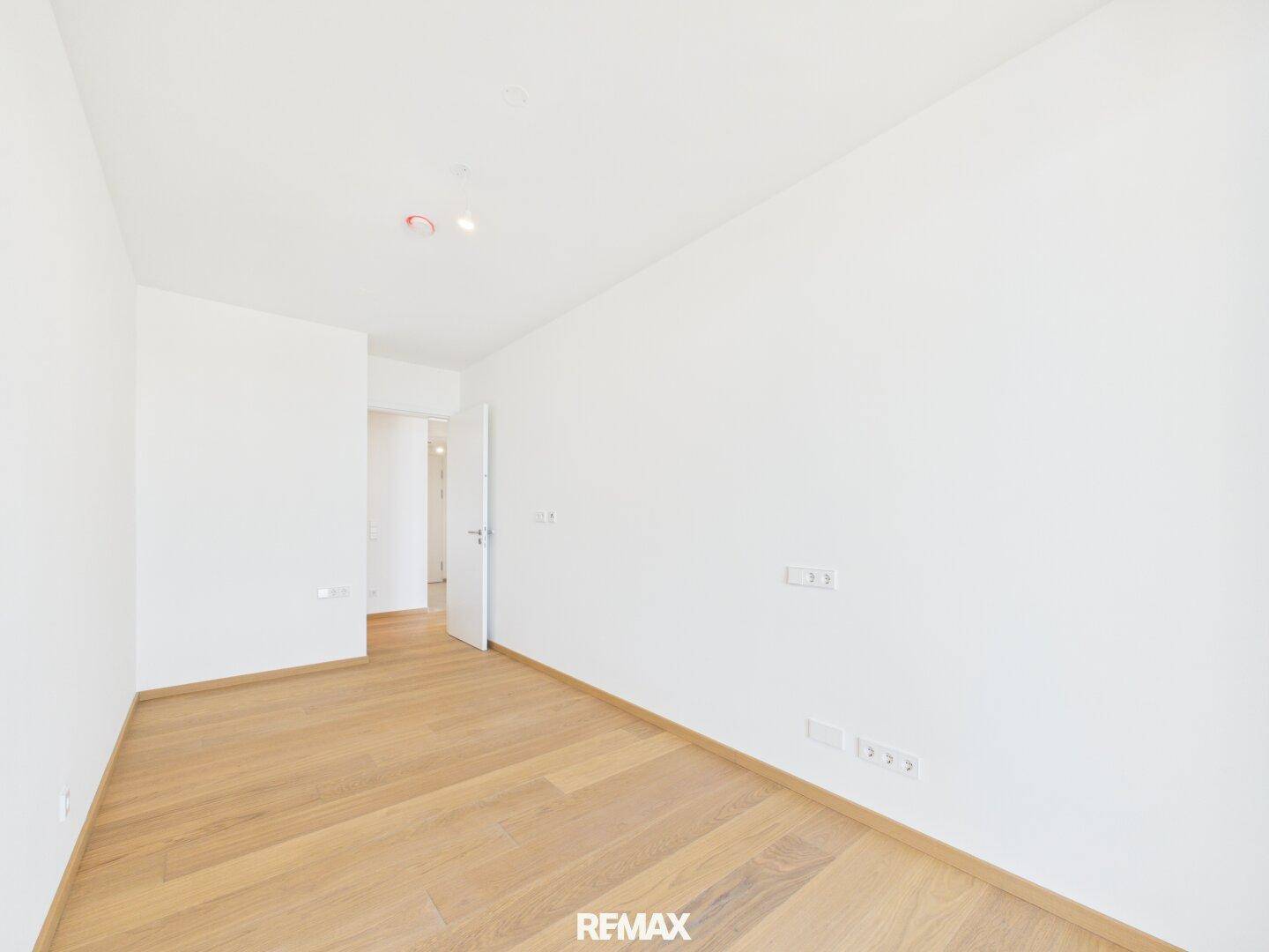 Geräumiges, helles Schlafzimmer mit Parkettboden und weißen Wänden, bereit zur Einrichtung.