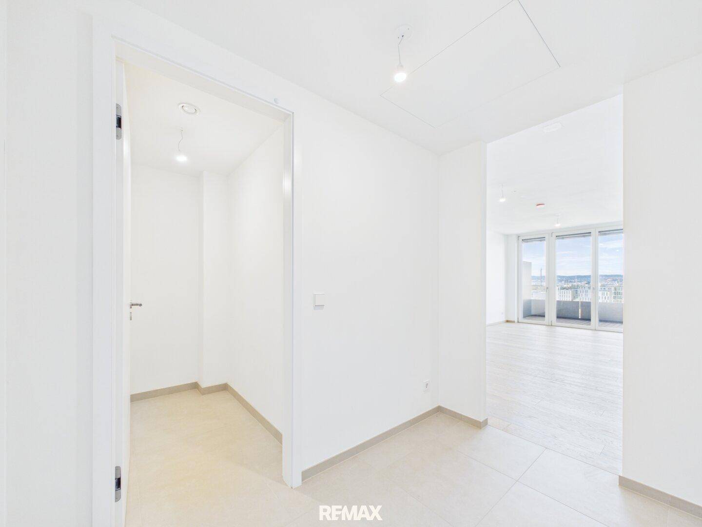 Heller Eingangsbereich mit Fliesenboden und Zugang zu einem lichtdurchfluteten Wohnraum.
