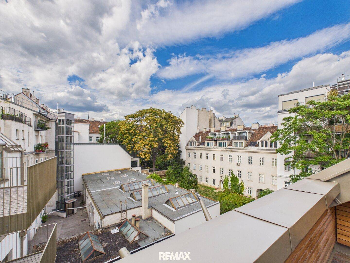 Weitläufiger Blick über die Dächer der Stadt mit viel Grün und einem blauen Himmel.
