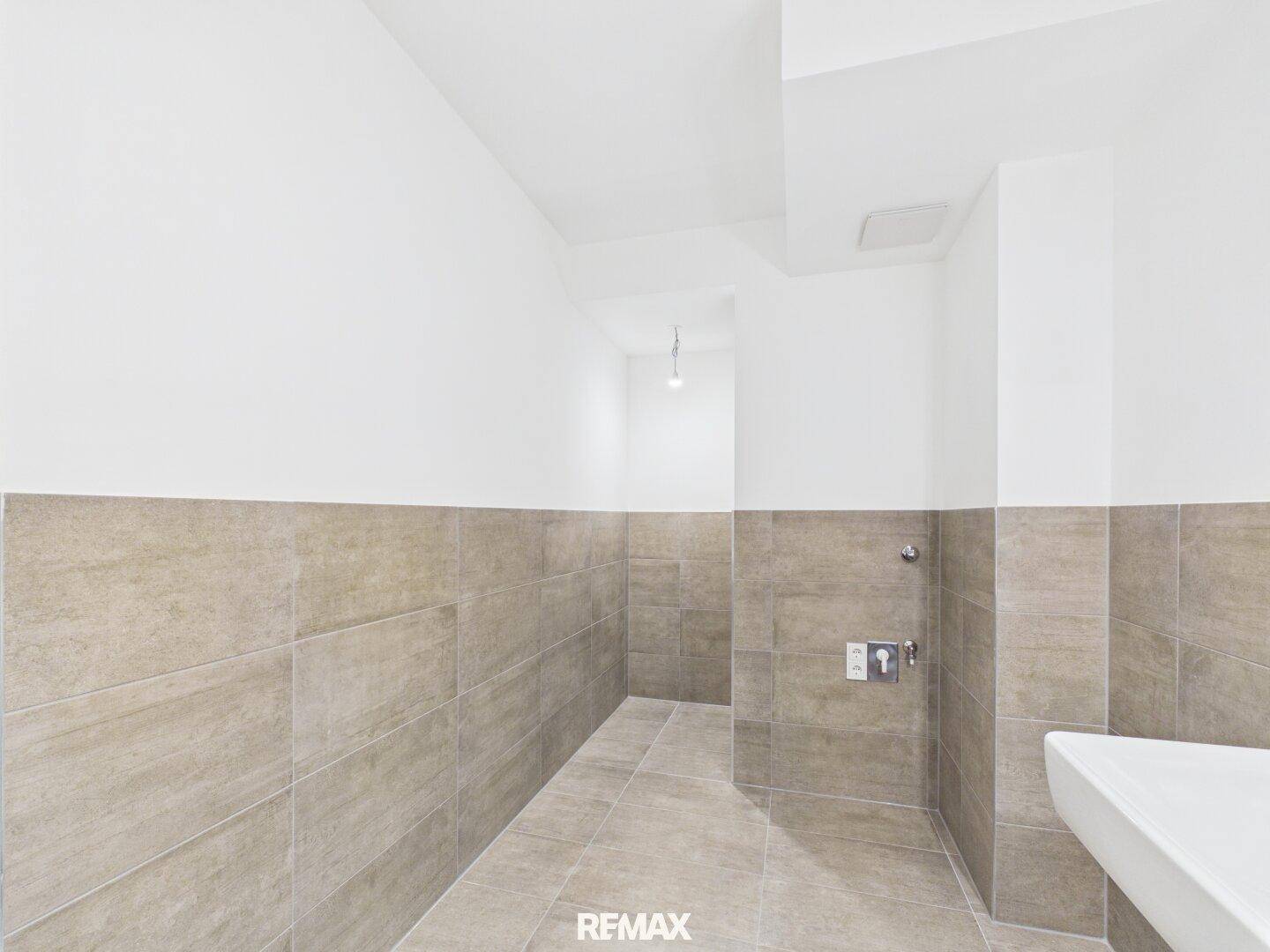 Helles Badezimmer mit modernen Fliesen an Wänden und Boden, vorbereitet für die Installation von Sanitäranlagen.