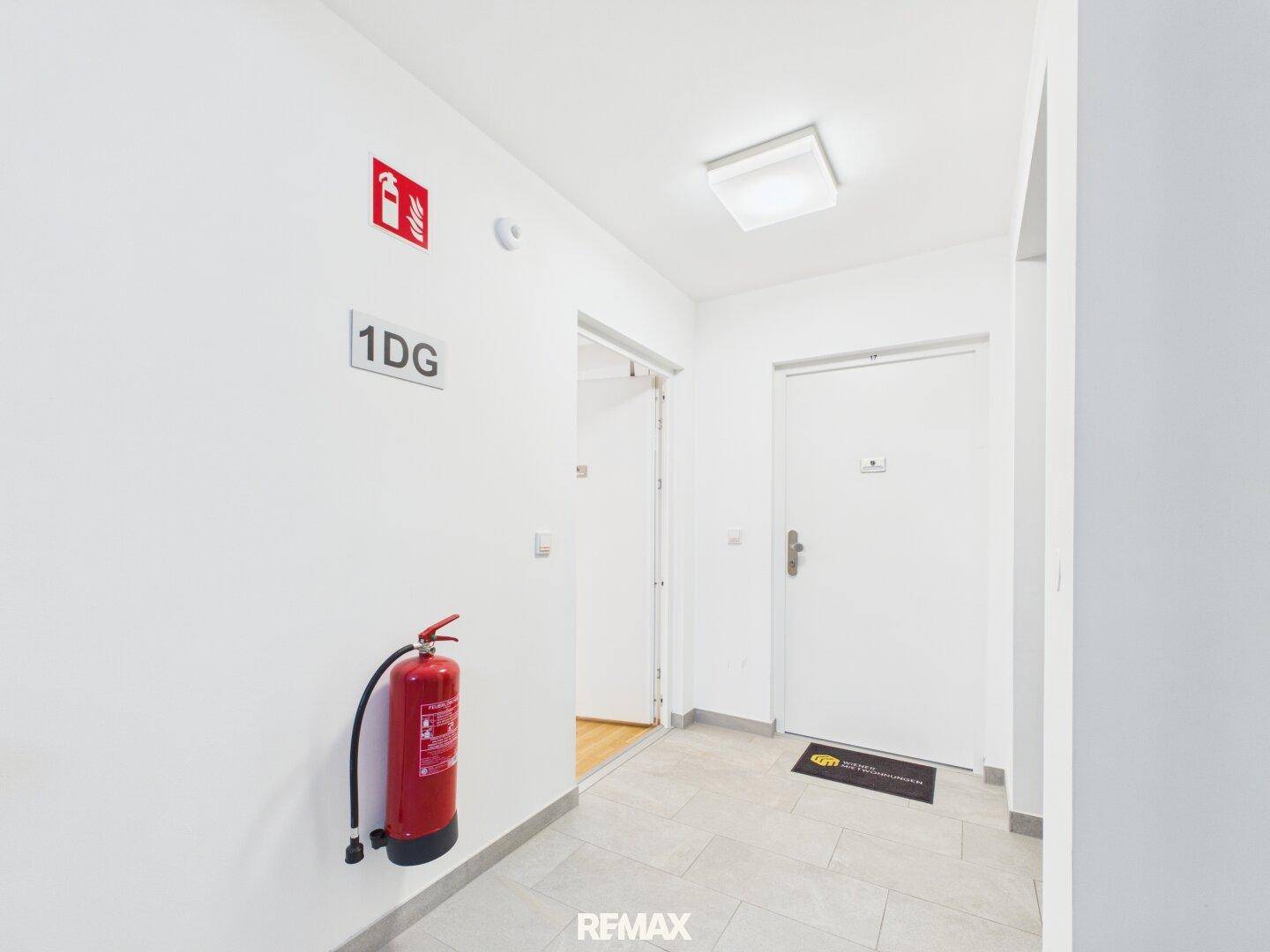 Heller Flur im Gebäude mit Brandschutzvorrichtungen und Zugang zu den Wohneinheiten.