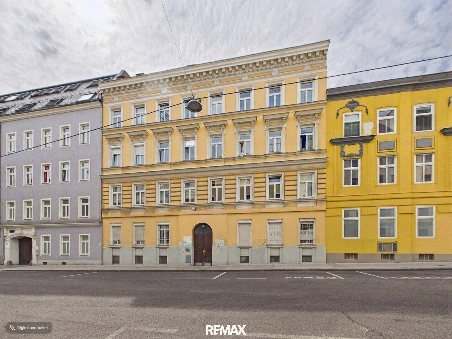 Historische Gebäudefassade in Gelb mit vielen Fenstern und klassischer Architektur.