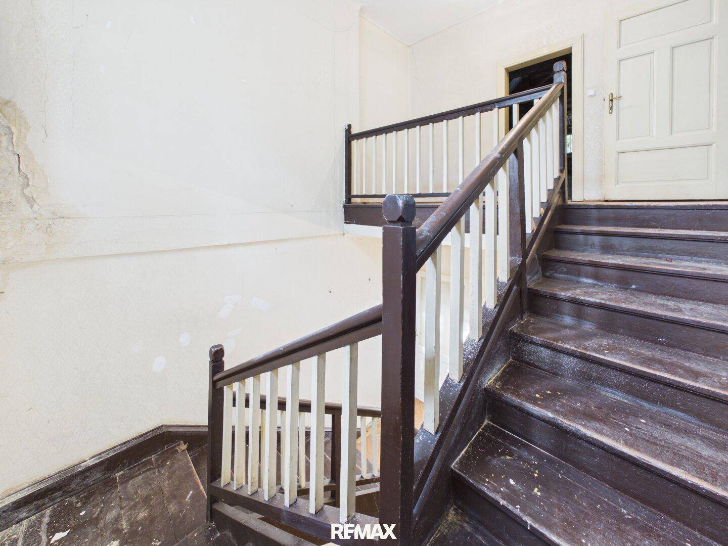 Detailansicht der Holztreppe mit Geländer in einem historischen Gebäude.