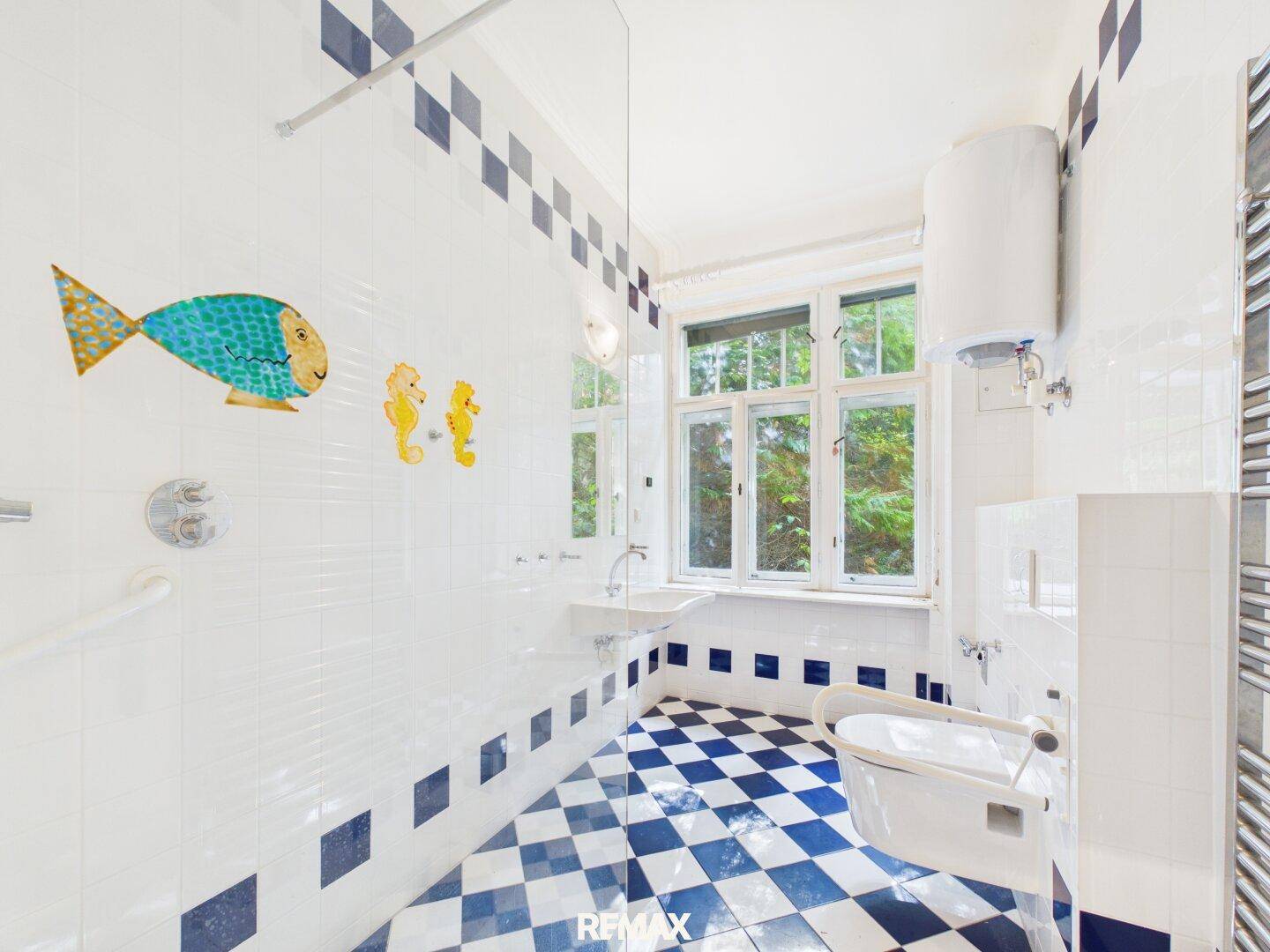 Modernes Badezimmer mit blauen und weißen Fliesen, Dusche und Fenster zum Garten.