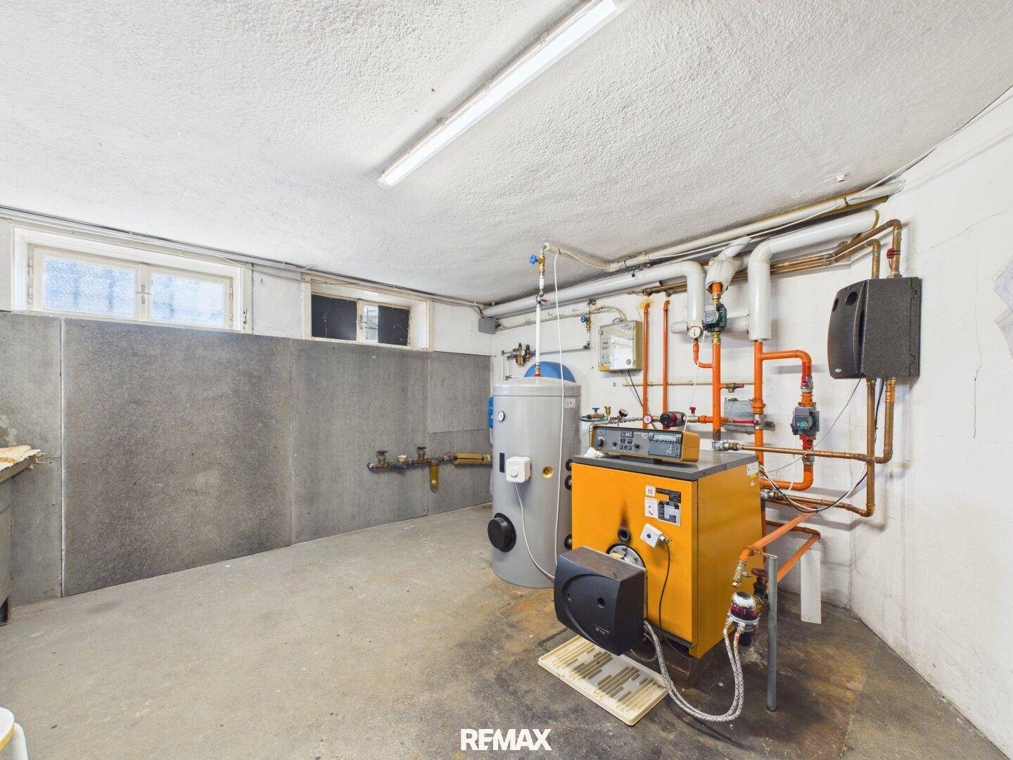 Technikraum im Keller mit Heizungsanlage, Rohren und Warmwasserspeicher.