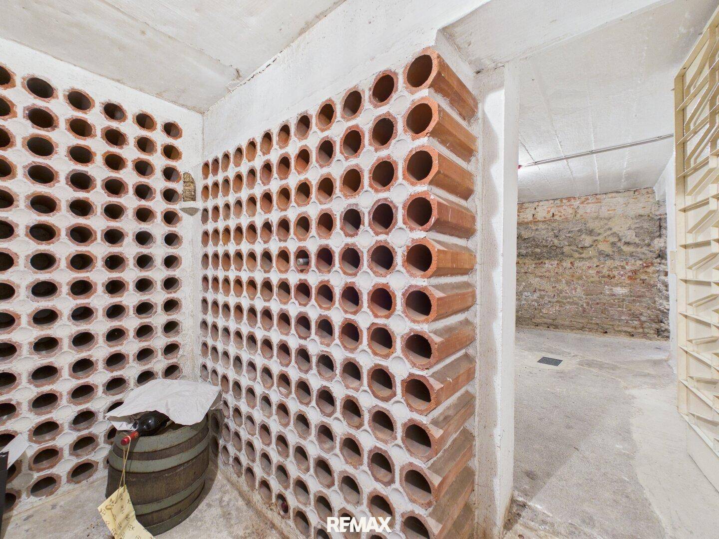 Rustikaler Weinkeller mit Terrakotta-Weinregalen und einem Holzfass.