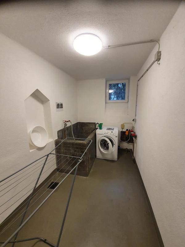 Waschküche im Keller mit Waschmaschine, großem Waschbecken und Wäscheständer.