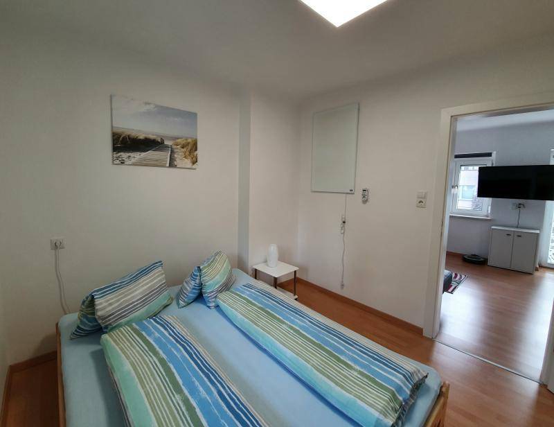 Schlafzimmer mit Doppelbett und Zugang zum Wohnbereich, hell und funktional eingerichtet.